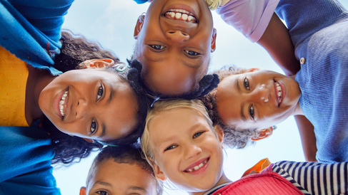 Children stood in a huddle looking down into the camera