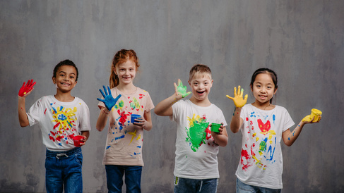 Children with painted hands and tshirts smiling in a line