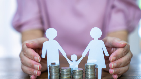 Paper stick people holding hands behind pile of coins