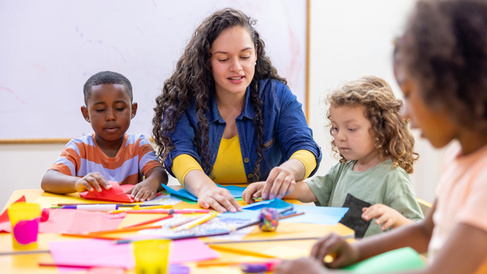 Worker sat with children doing arts and crafts
