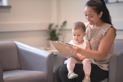 Baby sat on a woman's lap while she completes an application