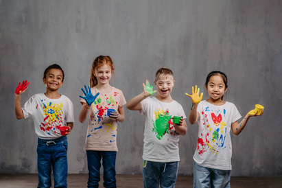 Children with painted hands and tshirts smiling in a line