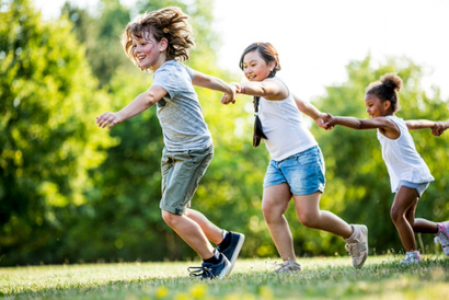 Children holding hands and running through a field