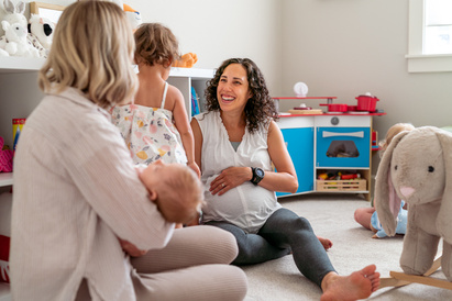 Pregnant and parent of newborn talking in a childcare setting
