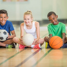 Children sat in a line with different sports balls