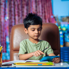 Boy using a calculator sat at a desk