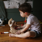 Child holding stethoscope to teddy bear