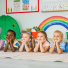 Nursery children laying in a row smiling