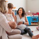 Pregnant and parent of newborn talking in a childcare setting