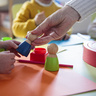 Child's and adults' hands playing with wooden toys