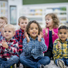 Groupf young children sat down clapping in a nursery setting