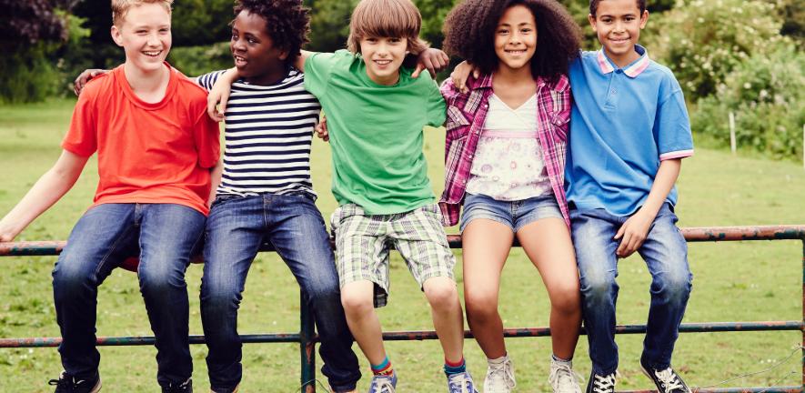 Children sitting on a gate arms around each other