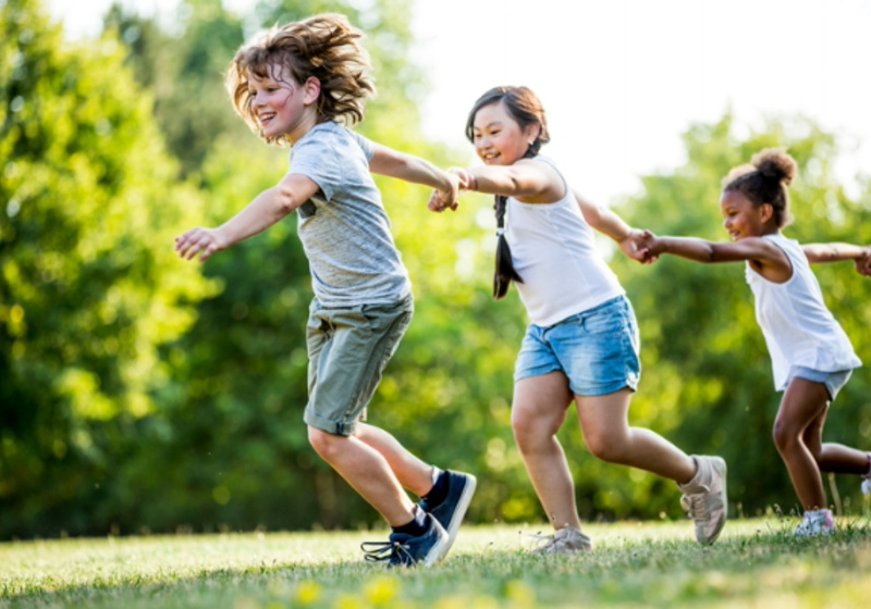 Children holding hands and running through a field