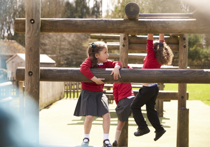School children playing on outdoor climbing frame